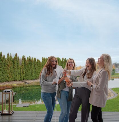 Gruppe von Freundinnen öffnet eine Flasche Champagner am Steg der Geinberg5 Private Spa Villas | © Spa Resort Geinberg