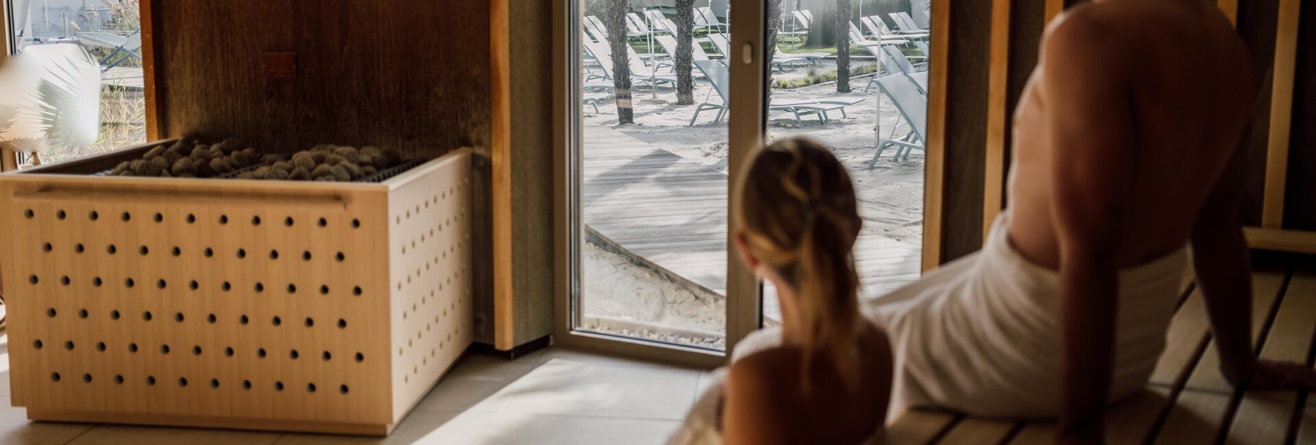 Paar genießt beim Sauna-Besuch die Aussicht auf die Strandfläche der Karibischen Saunawelt im Spa Resort Geinberg | © Spa Resort Geinberg / Chris Perkles