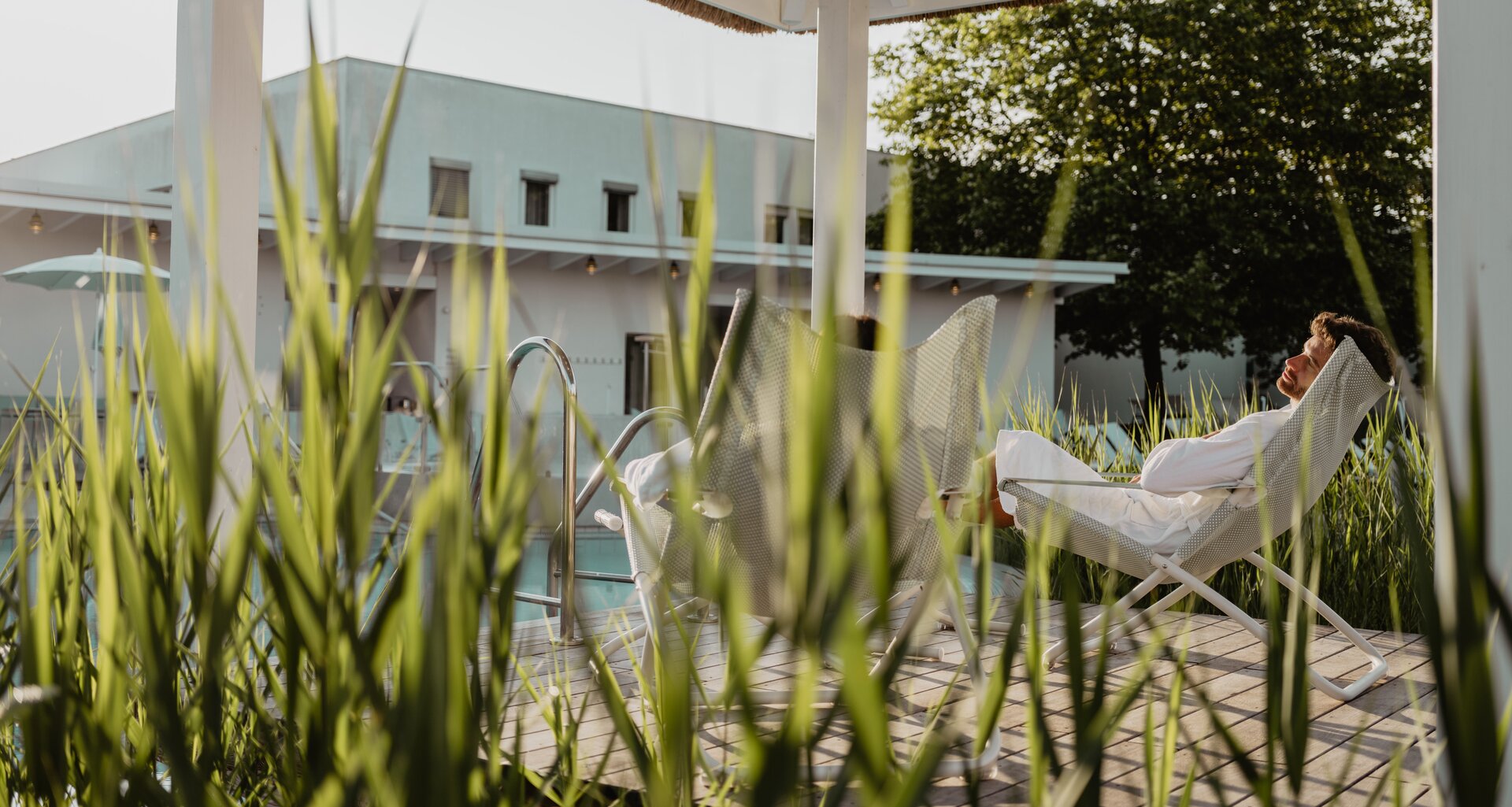 Paar genießt die Sonnenstrahlen im idyllischen Ambiente unter dem Pavillon der Karibischen Saunawelt | © Spa Resort Geinberg / Chris Perkles