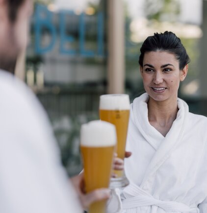 Paar im Bademantel genießt ein kühles Bier im Sauna-Bistro des Spa Resort Geinberg | © Spa Resort Geinberg / Chris Perkles