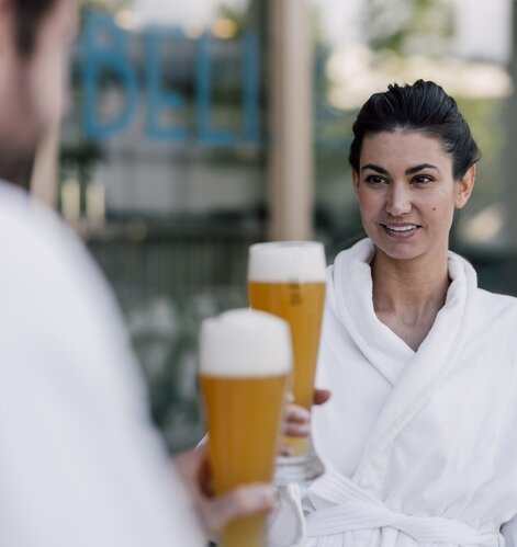 Paar im Bademantel genießt ein kühles Bier im Sauna-Bistro des Spa Resort Geinberg | © Spa Resort Geinberg / Chris Perkles