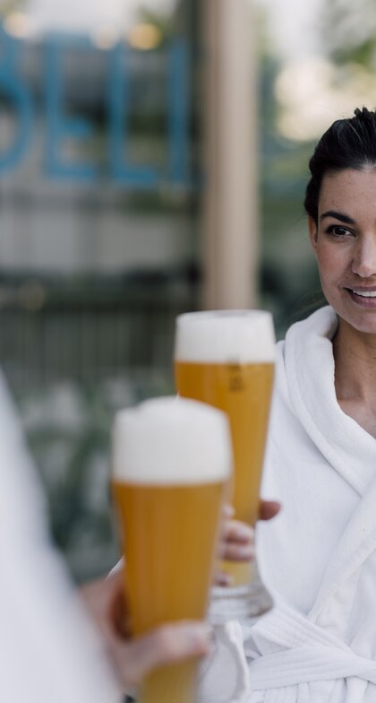 Paar im Bademantel genießt ein kühles Bier im Sauna-Bistro des Spa Resort Geinberg | © Spa Resort Geinberg / Chris Perkles