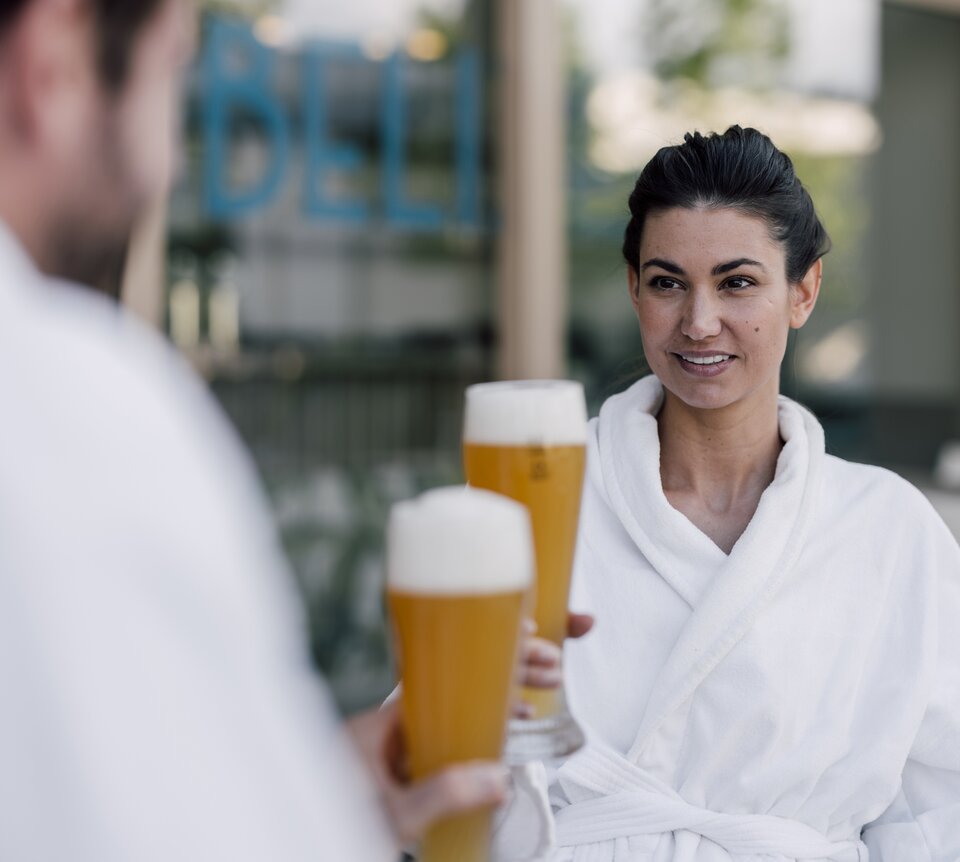 Paar im Bademantel genießt ein kühles Bier im Sauna-Bistro des Spa Resort Geinberg | © Spa Resort Geinberg / Chris Perkles