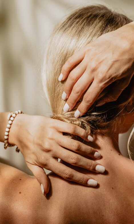 Blonde Dame streicht sich die Haare aus dem Nacken und fühlt sich vollkommen wohl im Vitality Spa | © Spa Resort Geinberg / Chris Perkles